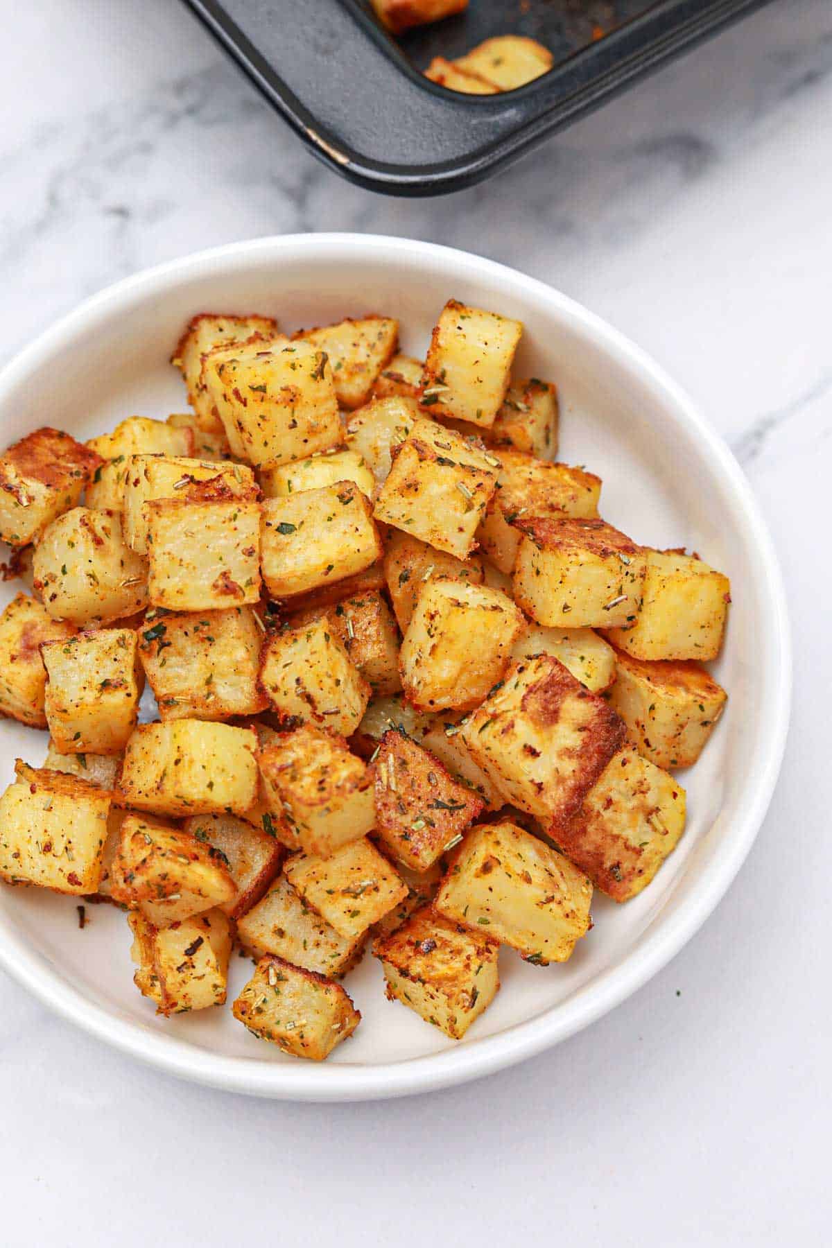 baked diced potatoes served  in a white bowl.
