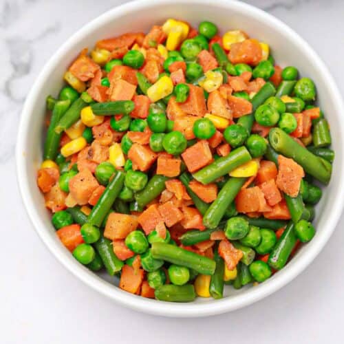 cooked frozen mixed vegetables served on a white plate.