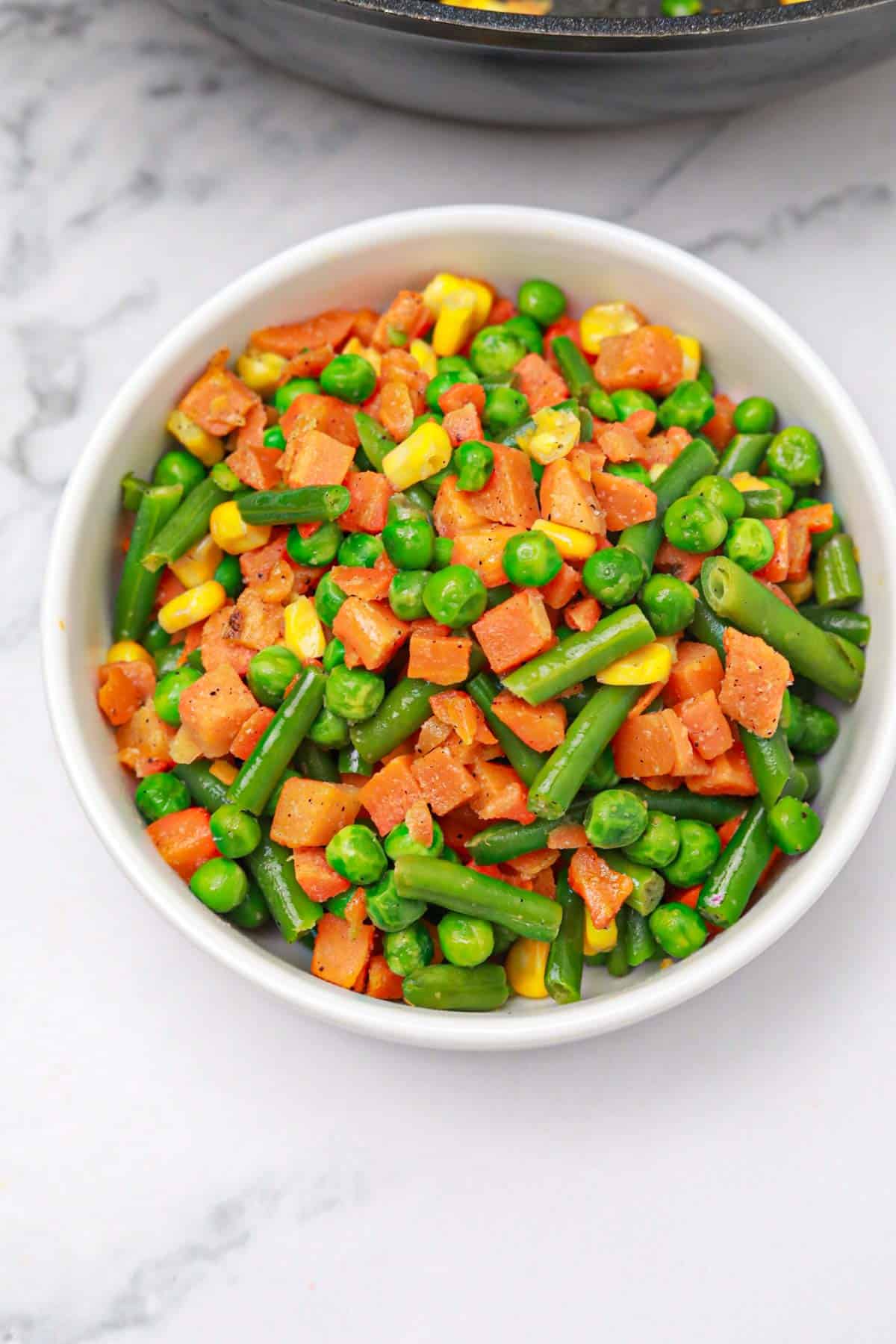 cooked frozen mixed vegetables served on a white plate.