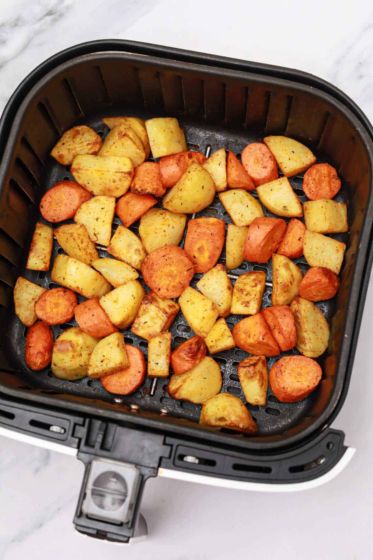 air fried carrots and potatoes in the air fryer basket.