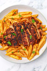 blackened chicken and pasta on a plate.