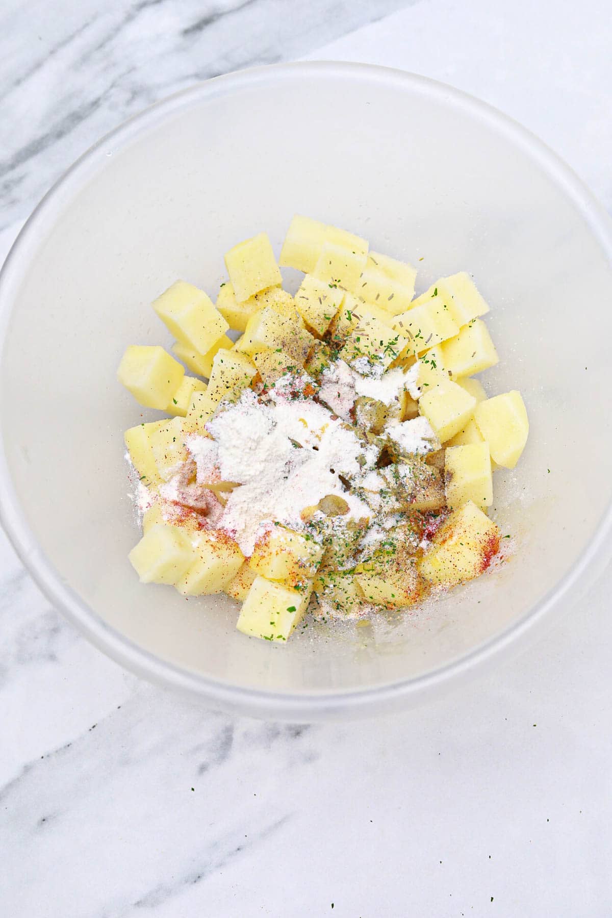 seasonings added to the potatoes in the bowl.