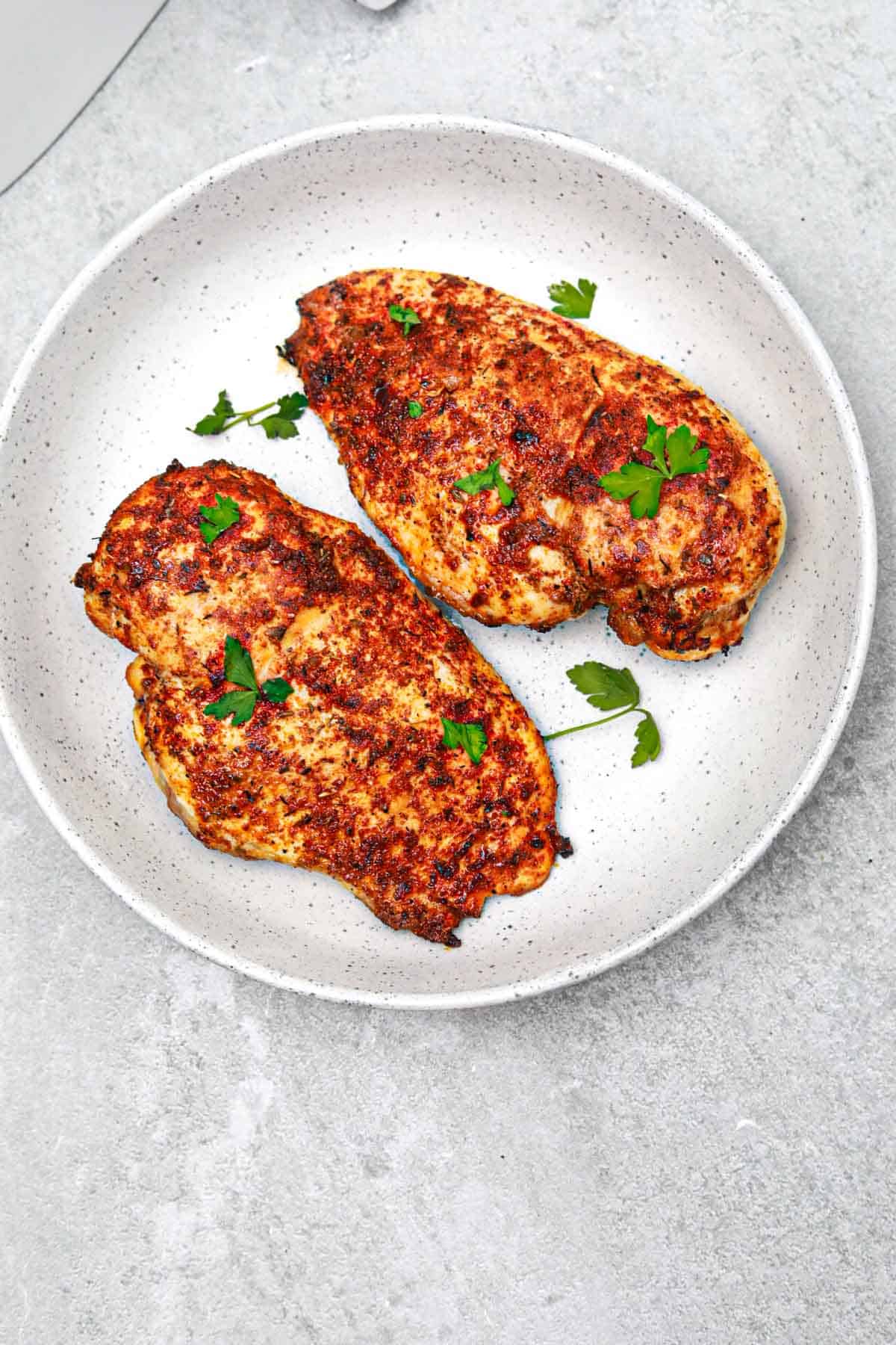 2 air fryer cajun chicken breasts on a plate.