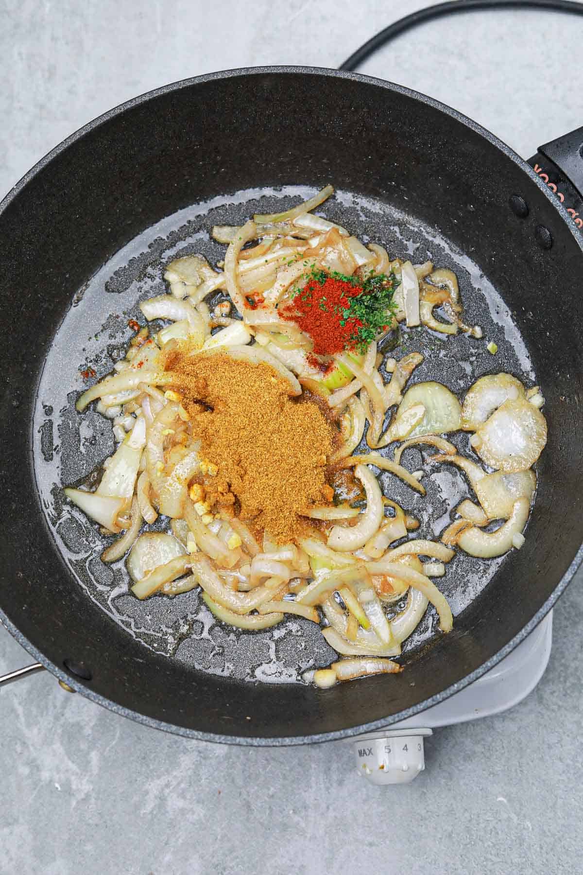 curry powder and other seasonings added to the skillet.