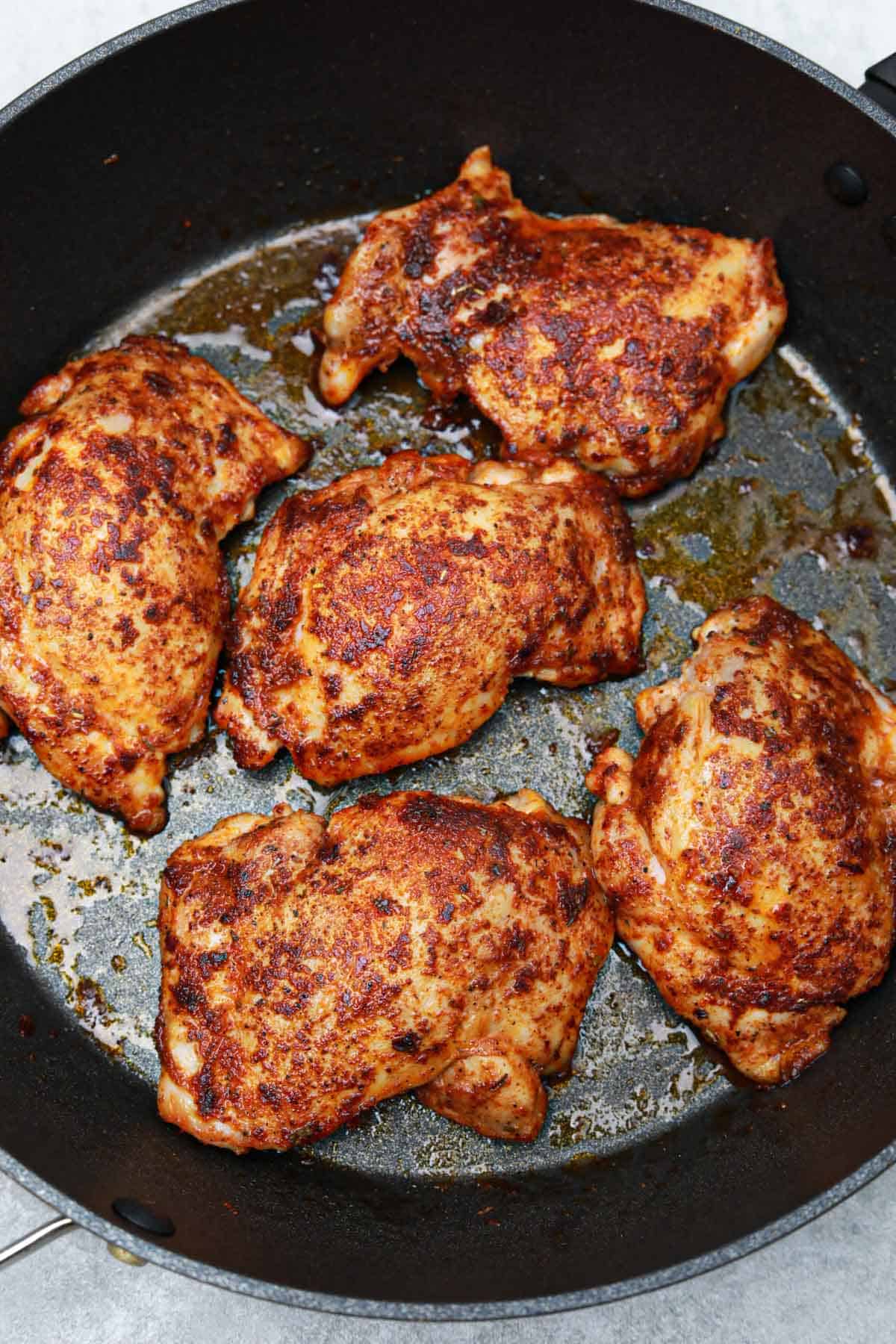 the fried boneless skinless chicken thighs in the frying pan.