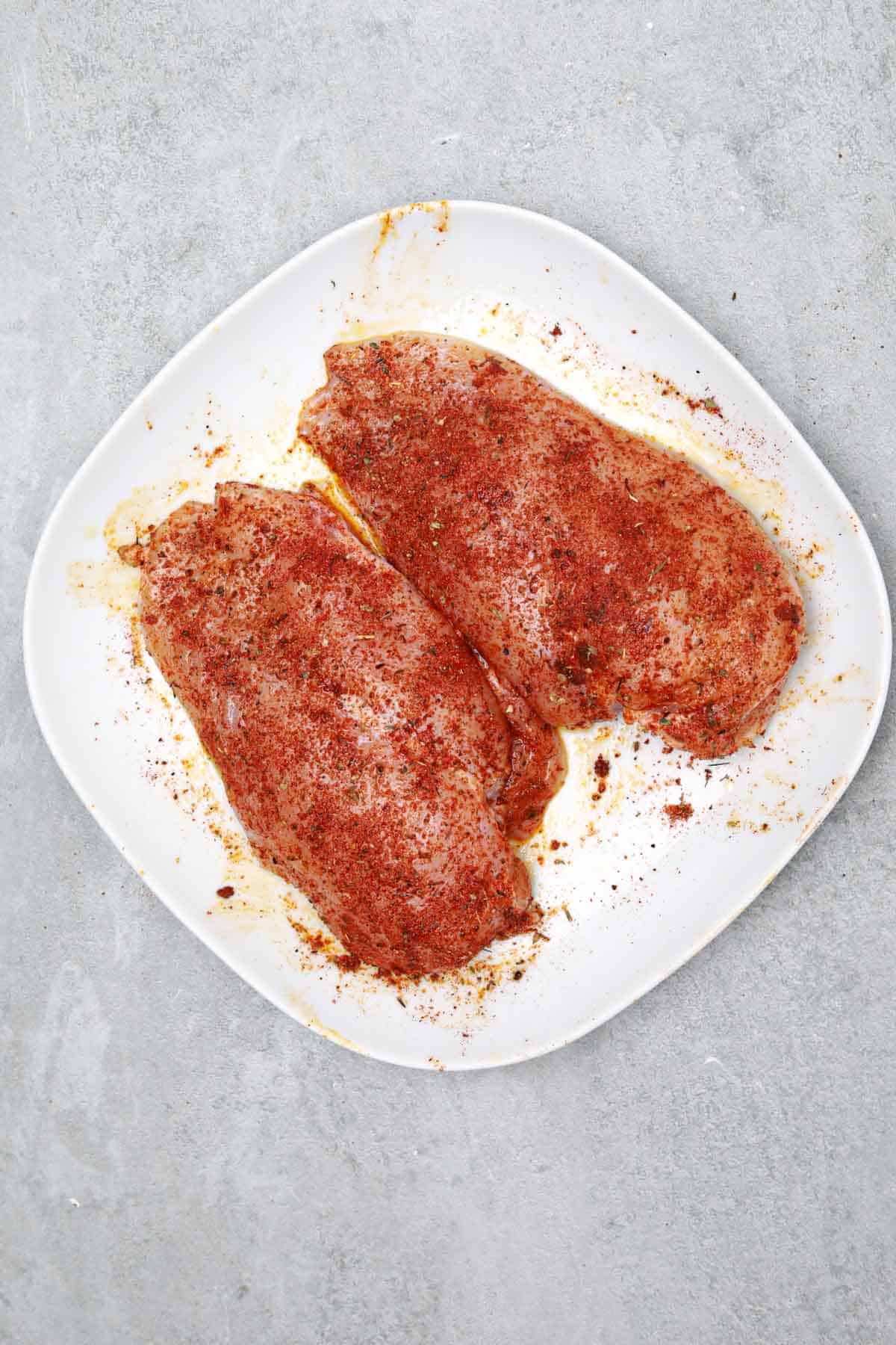 Cajun seasoned chicken breasts on a white plate.