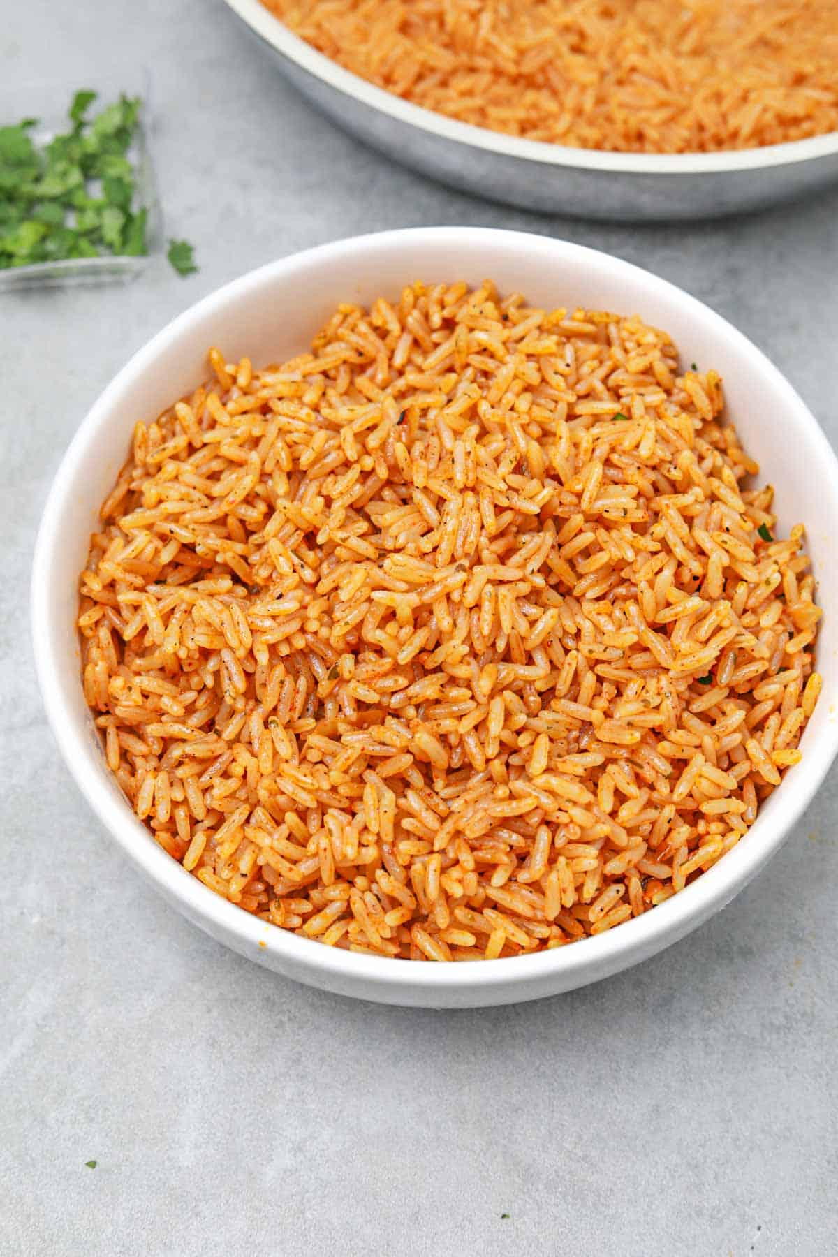 seasoned rice served in a white bowl with the remaining in the pan.