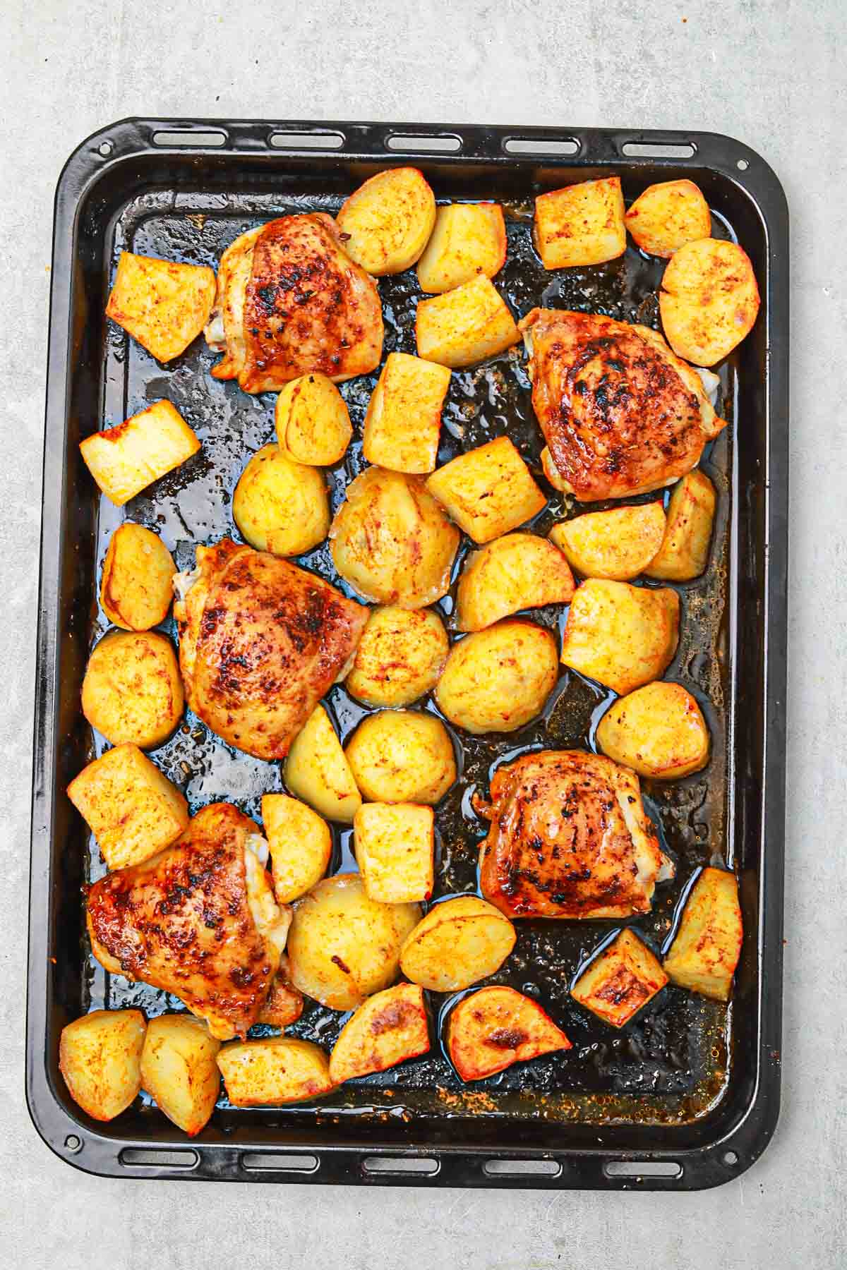 cooked chicken thighs and potatoes in a baking pan.