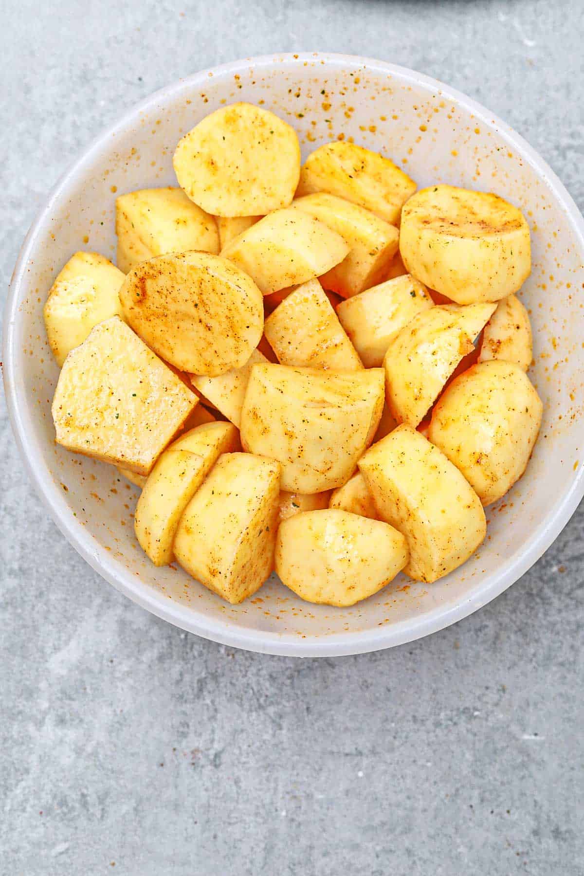 peeled, cut and seasoned potatoes in a bowl.