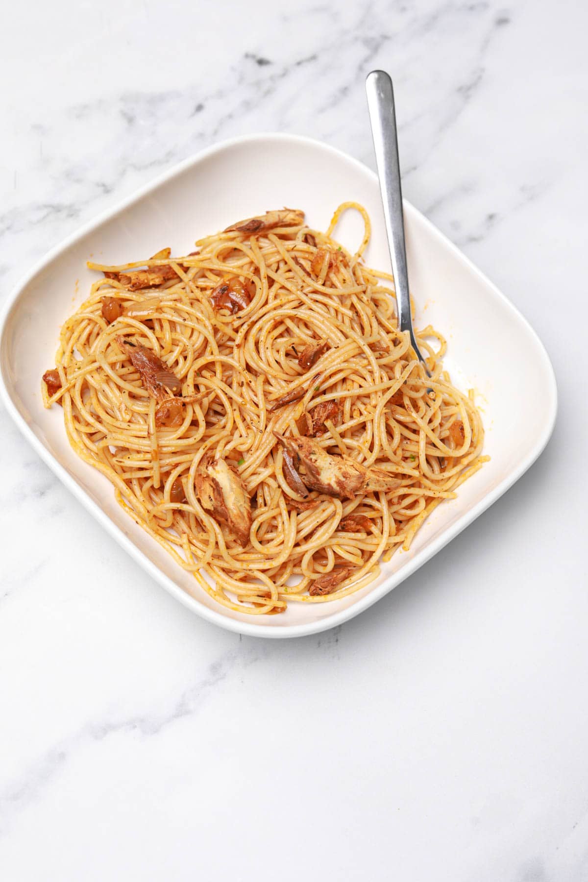 canned mackerel pasta served in a white pasta bowl.
