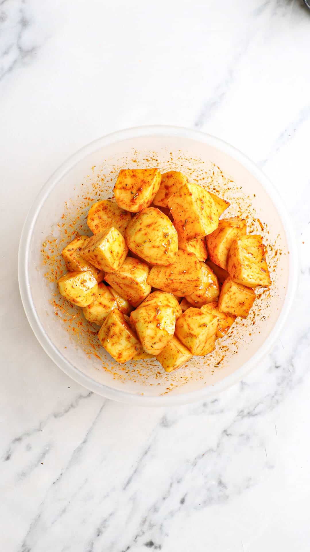 potatoes and seasoning mixed in a bowl.