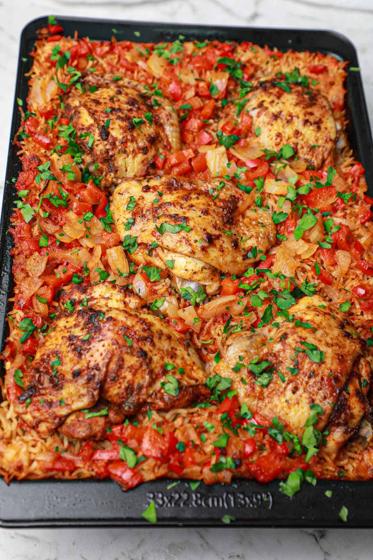 Baked chicken thighs and rice in baking pan.