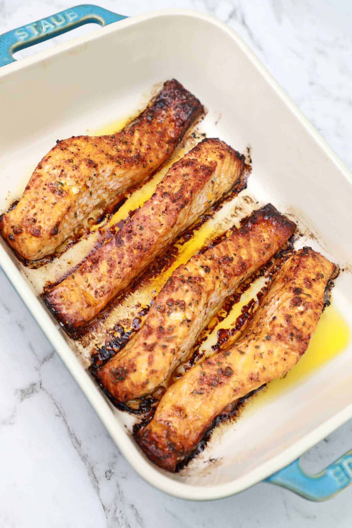 broiled salmon fillets in a baking dish.