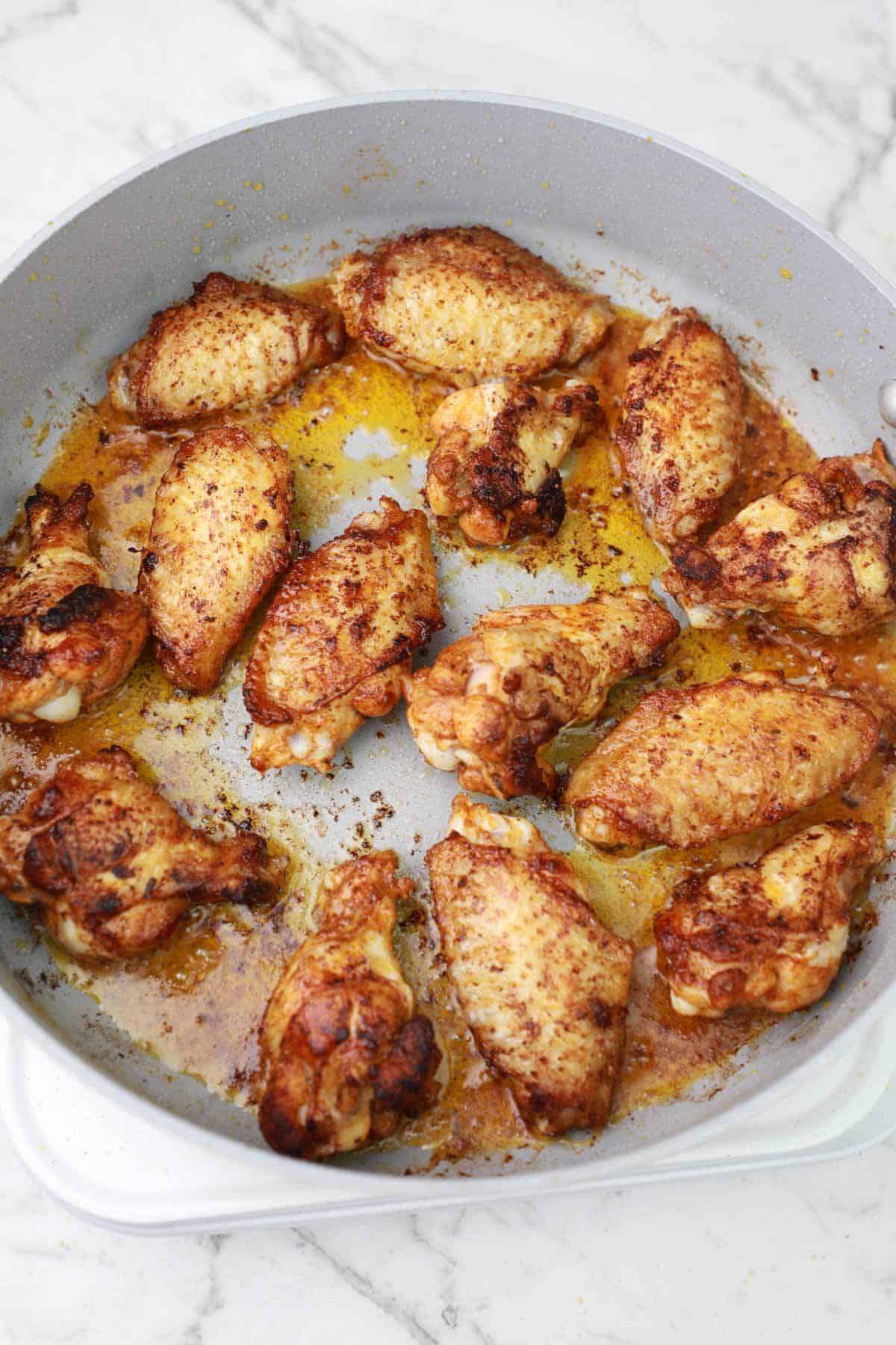 pan frying chicken wings in a frying pan.