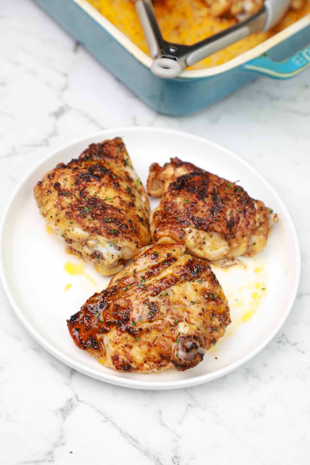 cooked chicken thighs served on a white plate.