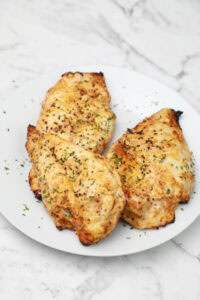 yogurt chicken breast served on a white plate.