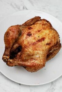 Deep fried whole chicken on a white plate.