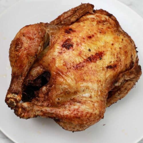 Deep fried whole chicken on a white plate.